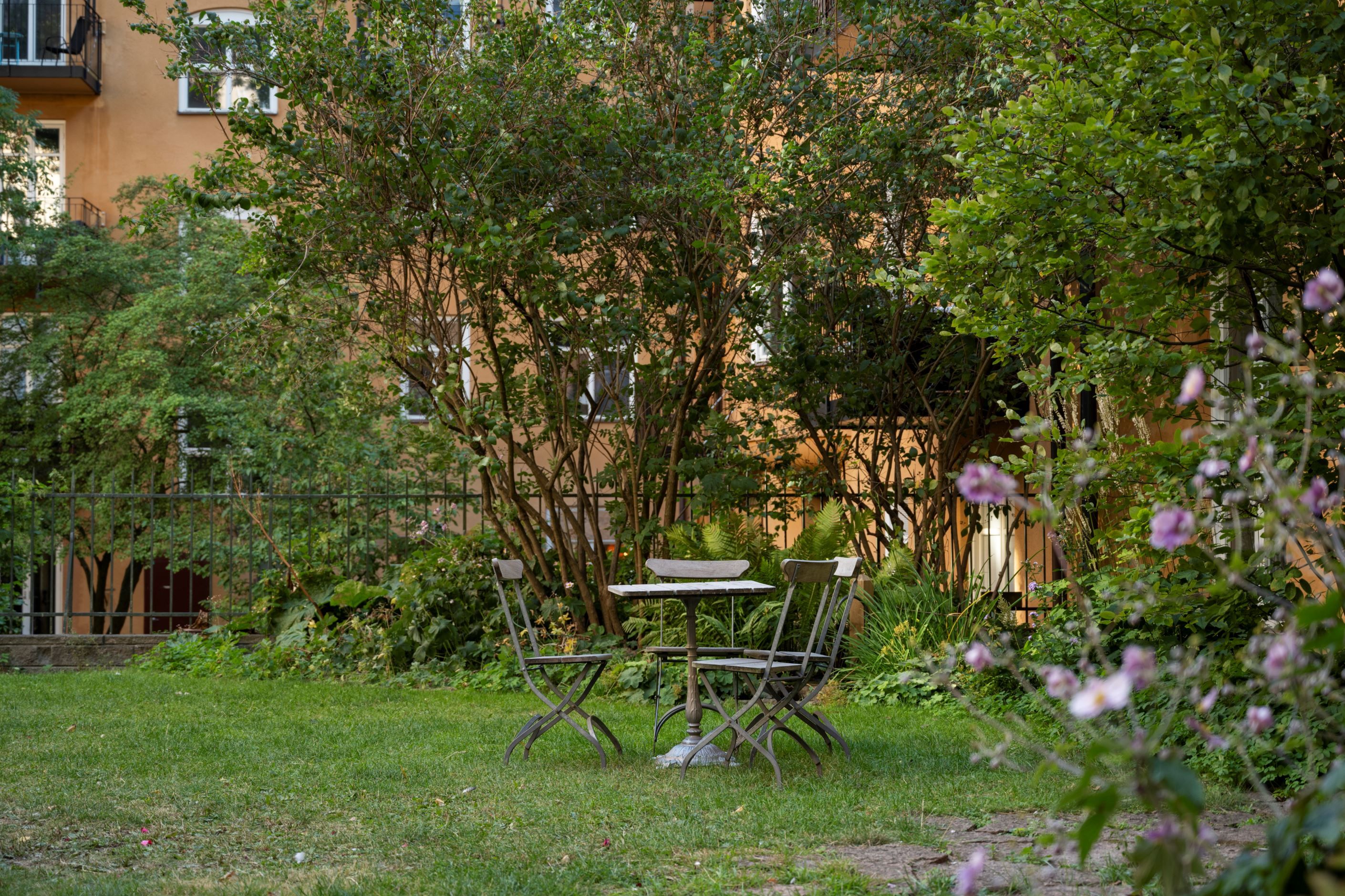 Lummig innergård med sittgrupp, grillplats och lekstuga