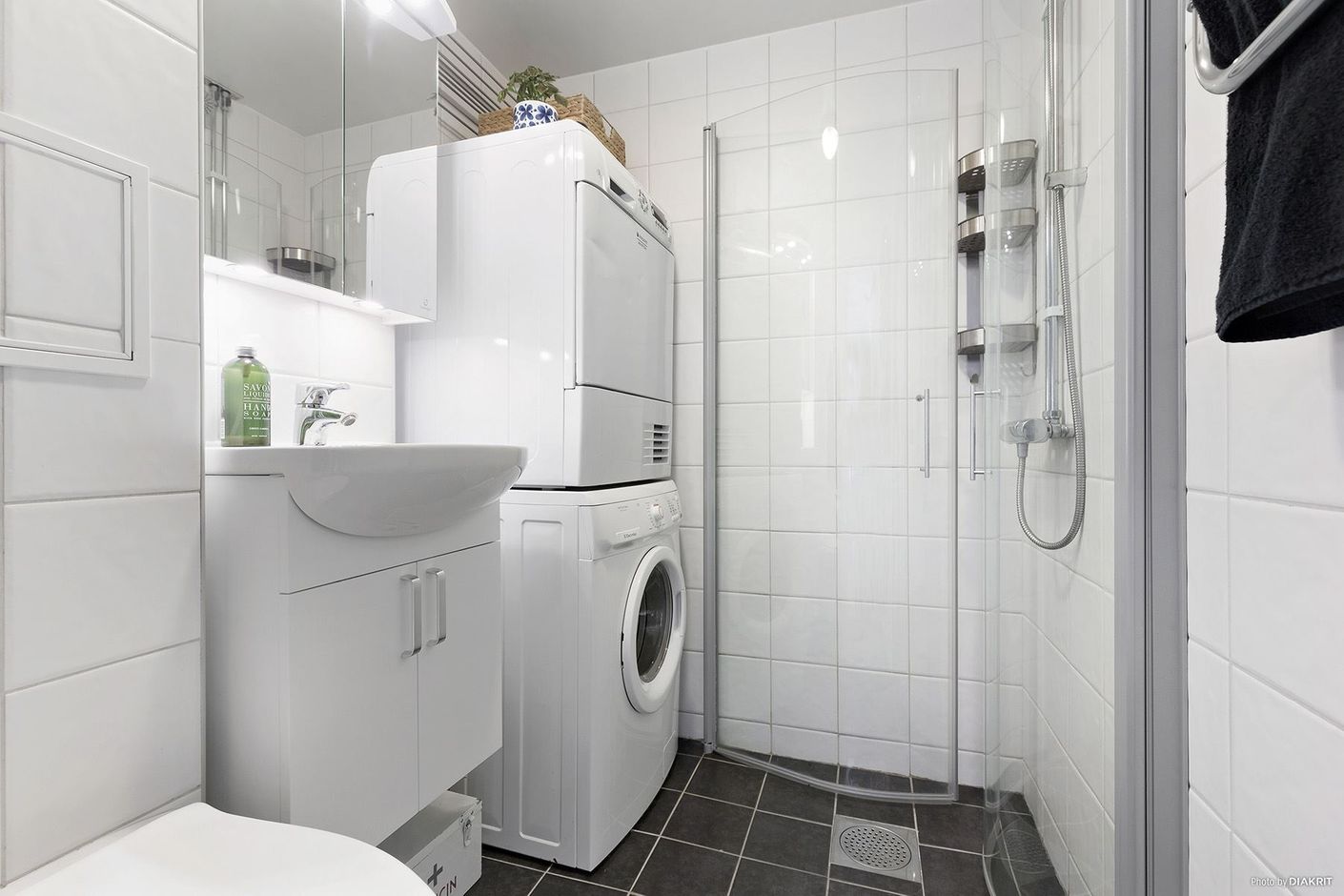 Snyggt helkaklat badrum med tvättmaskin och torktumlare