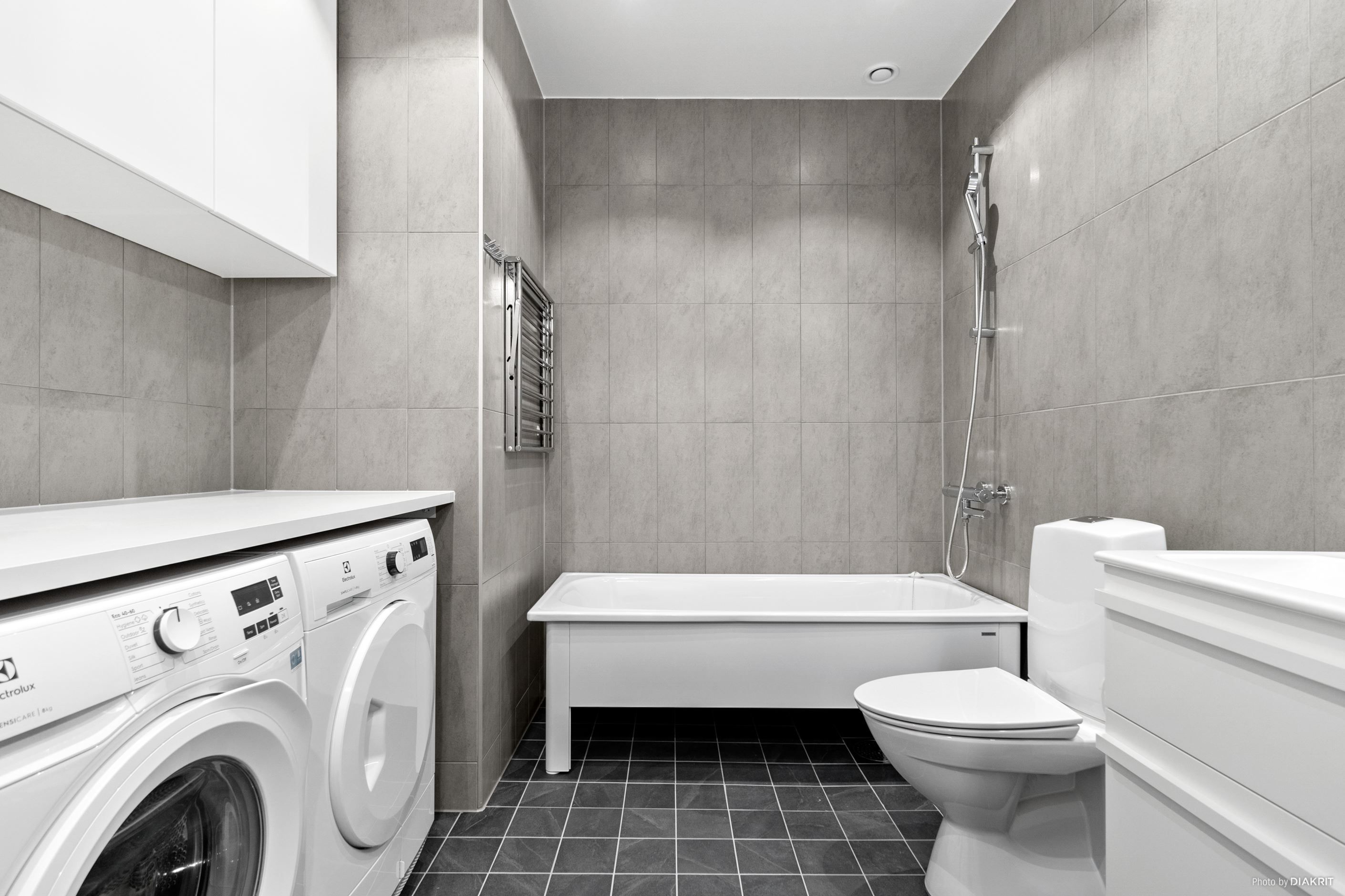 Helkaklat badrum med badkar, tvättmaskin och torktumlare