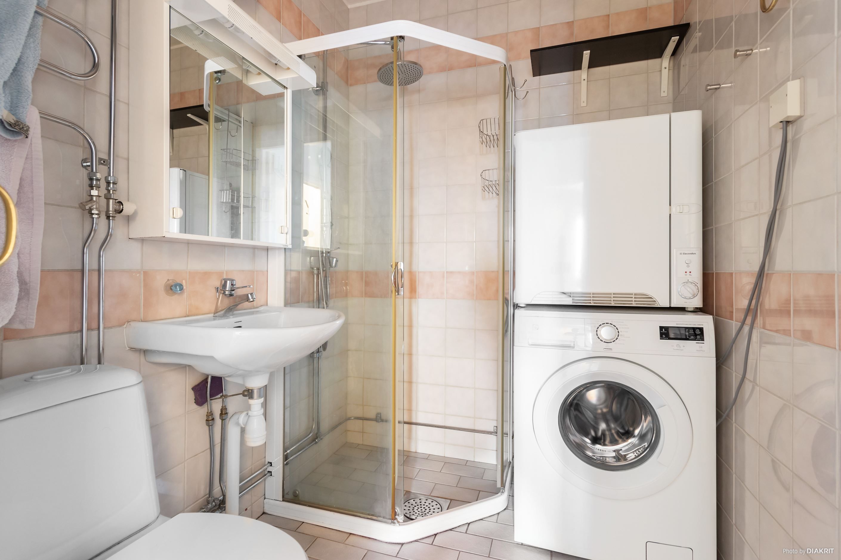 Helkaklat badrum med tvättmaskin och torktumlare