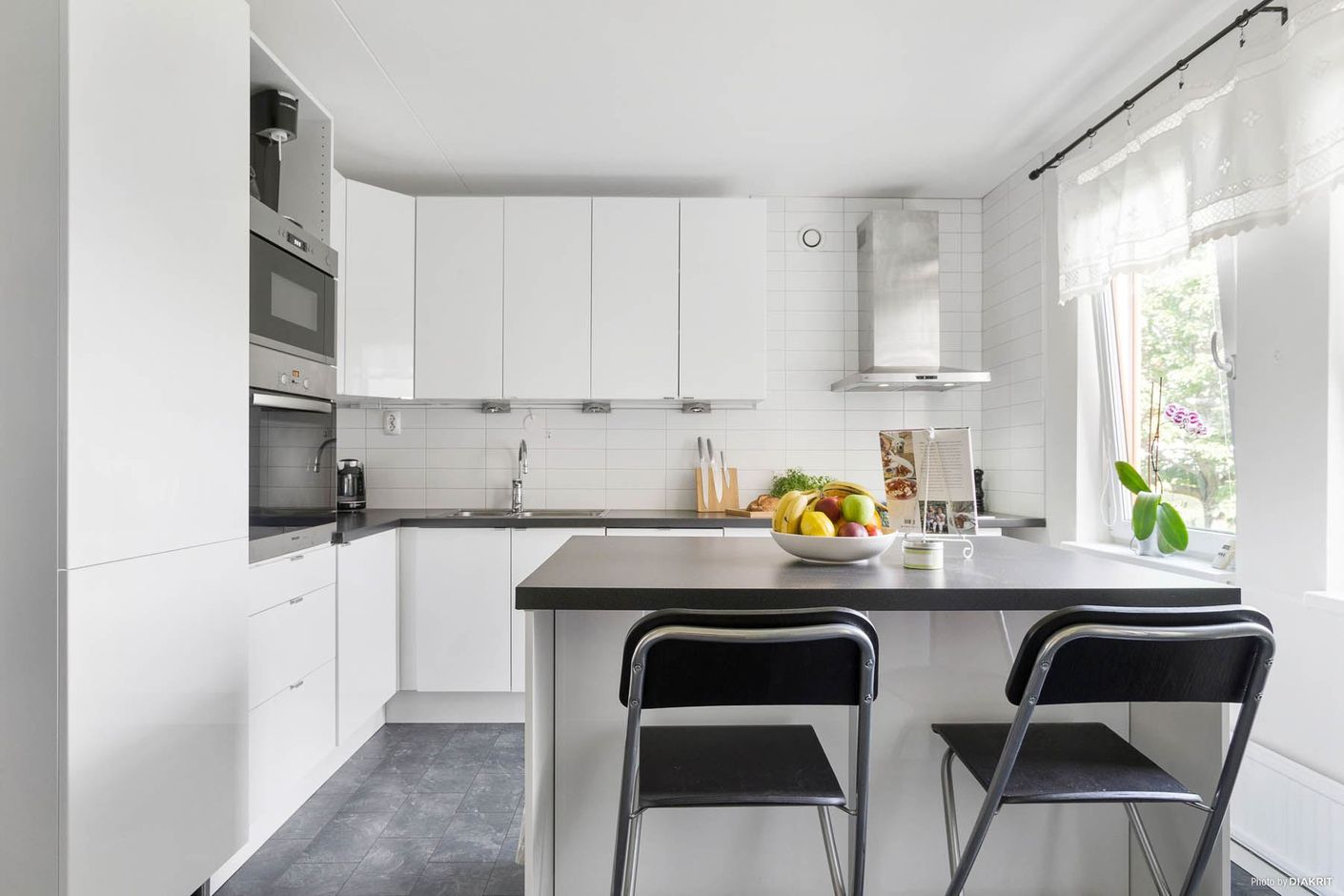 Vitt, ljust och modernt kök med ljusinsläpp från två fönster