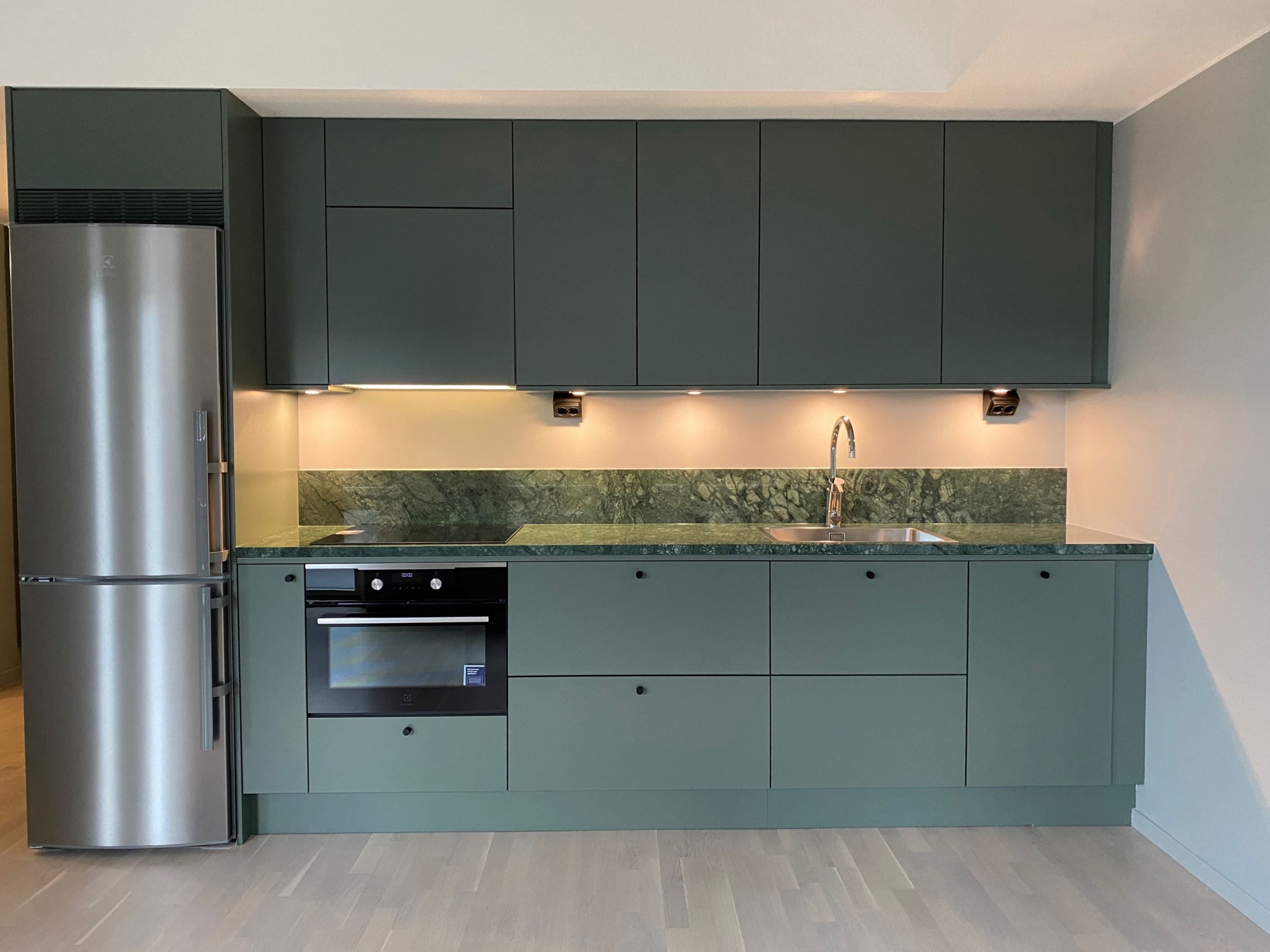 Kök från Vedum i grönt med bänkskiva och stänkskydd i sten samt vitvaror från Electrolux