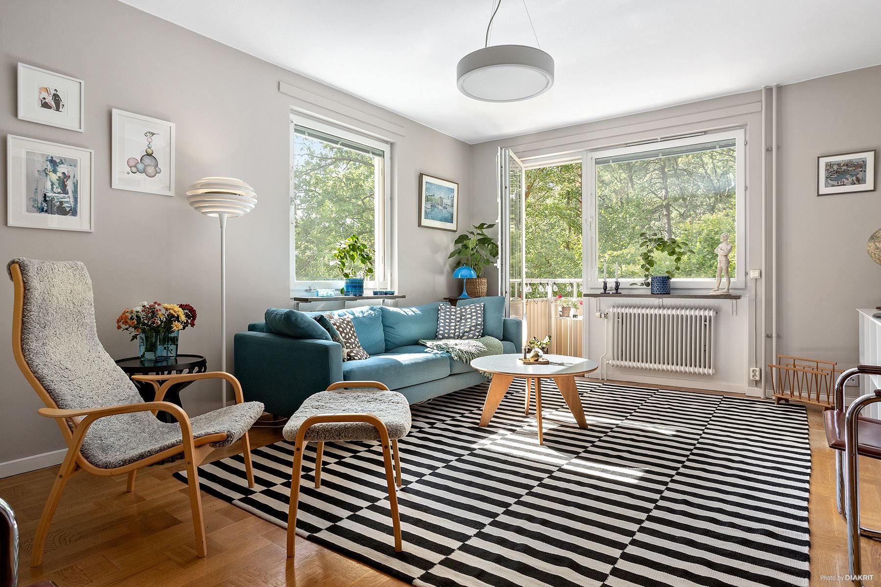 Ljust vardagsrum med fönster i två väderstreck och utgång till balkong